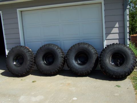 1995 Ford Bronco - Four off-road tires are displayed in front of a garage, not a 1995 Ford Bronco.