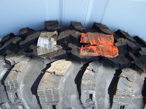 1995 Ford Bronco - A close-up view of a off-road tire, showing its tread pattern and attached product labels.