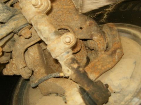 1993 Ford Bronco - Close-up of heavily rusted vehicle suspension parts and a tire.