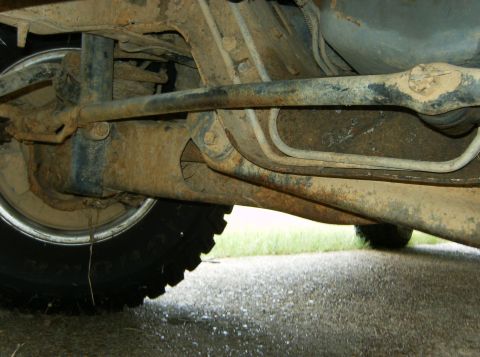1993 Ford Bronco - Close-up view of the rusty undercarriage and suspension components of a vehicle.