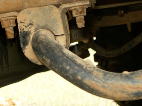 1993 Ford Bronco - This image shows a close-up view of a dirty and rusty suspension component, likely part of a vehicle's undercarriage.