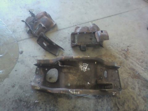 1992 Ford F-350 - Several heavily rusted metal frame components are scattered on a concrete surface, appearing to be salvaged parts.