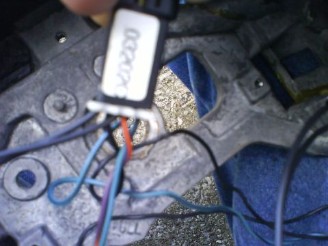 2003 Ford Crown Victoria - A close-up view of a wiring harness connected to a metal bracket, with visible text on a label.
