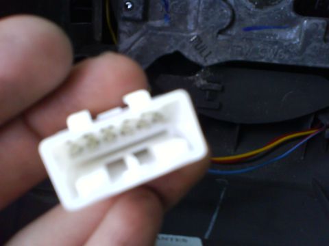 2003 Ford Crown Victoria - A hand holds a white wiring harness connector with visible wires, suggesting a part replacement or repair.