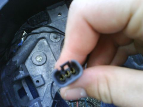 2003 Ford Crown Victoria - Hand holding a three-pin electrical connector with wiring visible in the background.