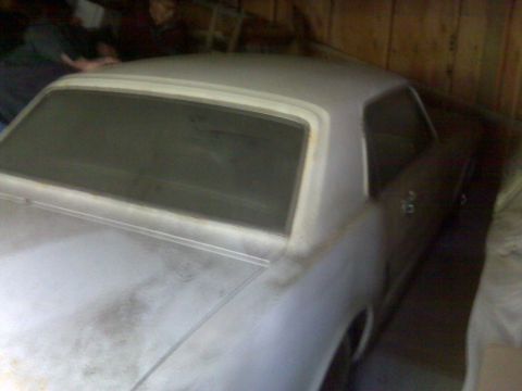 1966 Ford Mustang - The rear of a car, possibly undergoing restoration, is shown in a dimly lit garage.