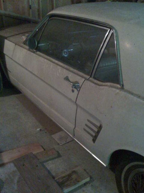 1966 Ford Mustang - This white coupe, believed to be a 1966 Ford Mustang, is parked indoors.