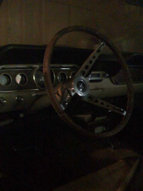 1966 Ford Mustang - The interior of a 1966 Ford Mustang shows a classic wood-rimmed steering wheel and dashboard.