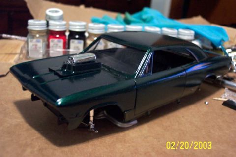 1991 Ford Crown Victoria LTD - A model car with a prominent hood scoop sits on a table next to jars of paint.