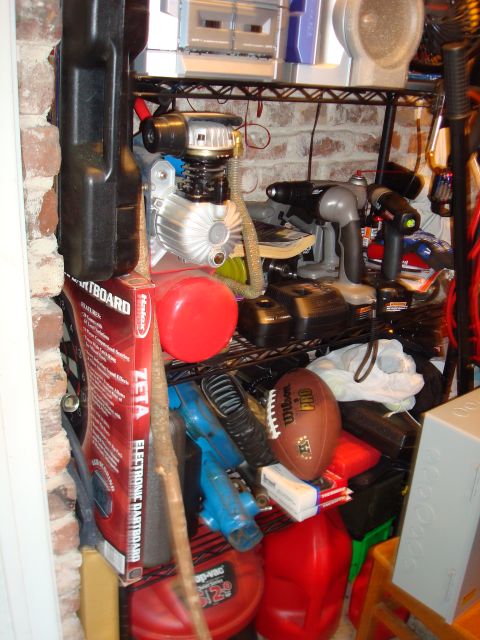 1977 Ford F-100 - Shelves in a garage are cluttered with various tools, an air compressor, and a football.