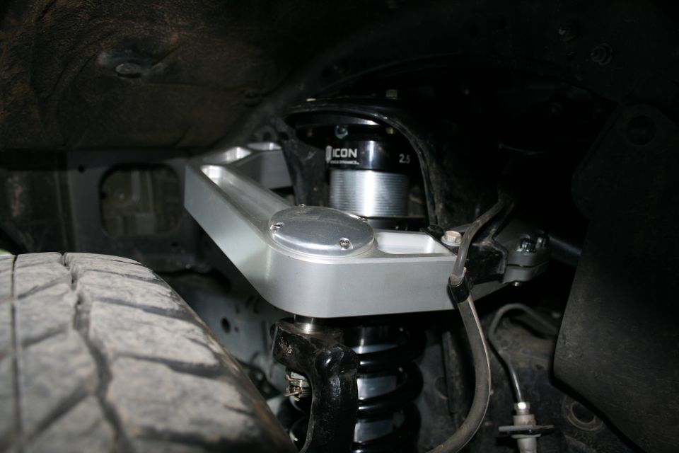 Close-up of an aftermarket upper control arm and ICON shock absorber assembly on a vehicle's suspension