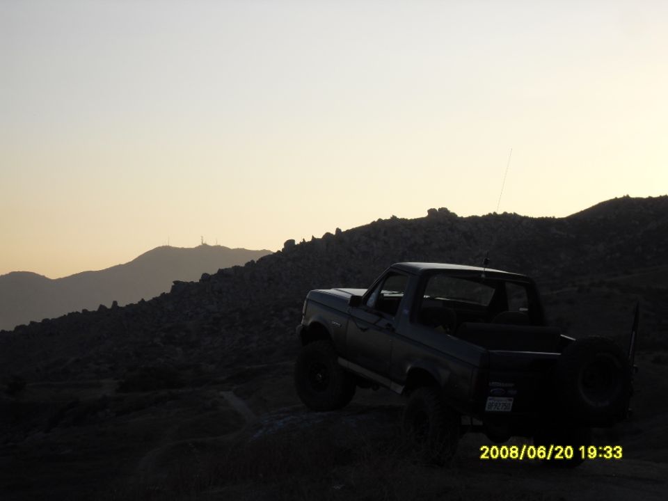 Ford Bronco parked on a rocky hill at sunset