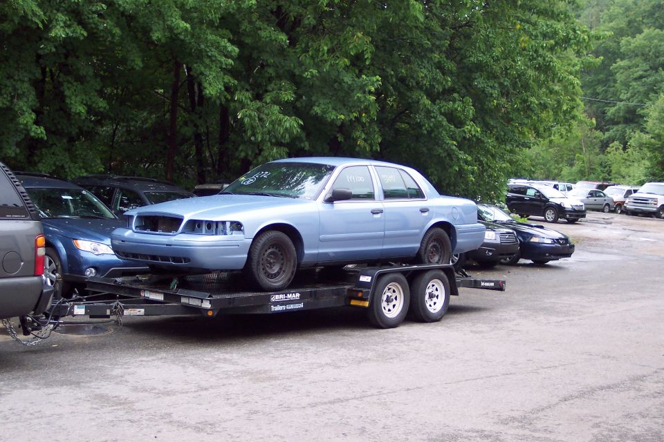 Light blue 2001 Ford Crown Victoria on trailer, front bumper missing
