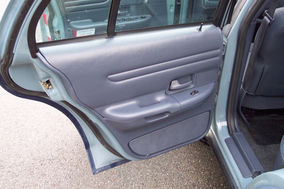 Interior of a light blue sedan, rear passenger door panel and seatbelt.