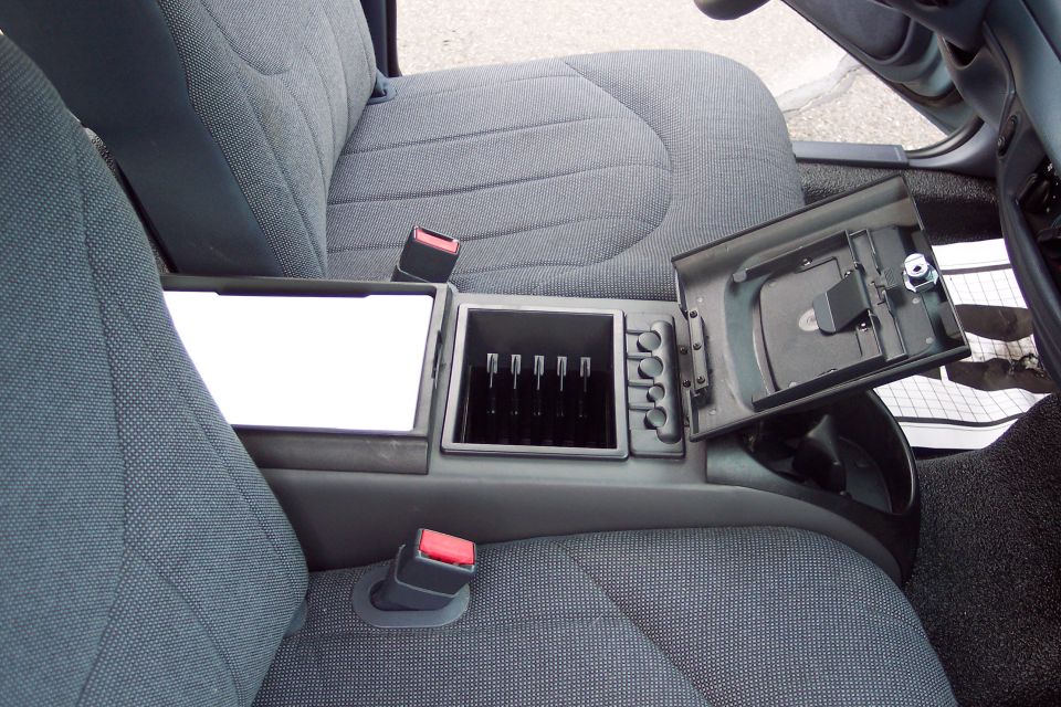 Interior of a car showing a center console with an open storage compartment and coin holder.