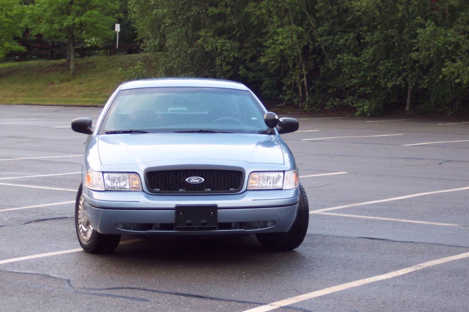 Light blue 2001 Ford Crown Victoria parked in a wet parking lot.
