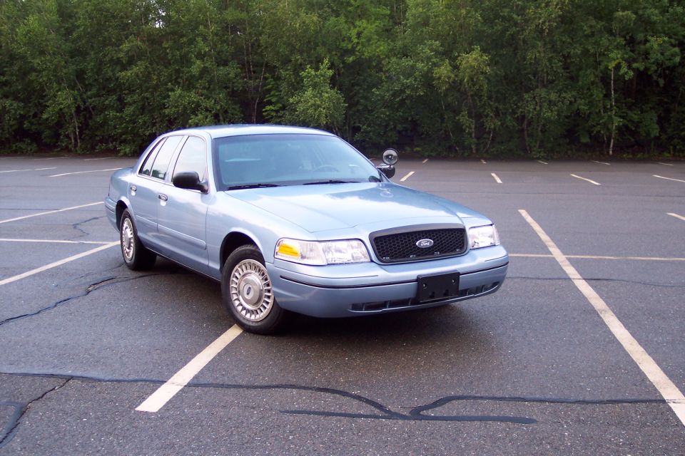 2001 Ford Crown Victoria sedan, light blue, parked in a lot.