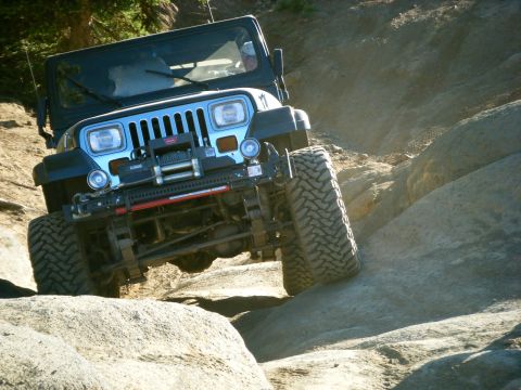 2005 Jeep Wrangler - A blue Jeep Wrangler is shown navigating a rocky, off-road trail with large tires and a winch mounted on the front bumper.