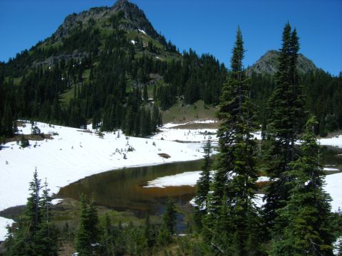 2005 Jeep Wrangler - A scenic view of a mountain landscape with snow-covered slopes and a body of water, surrounded by evergreen trees under a clear blue sky.