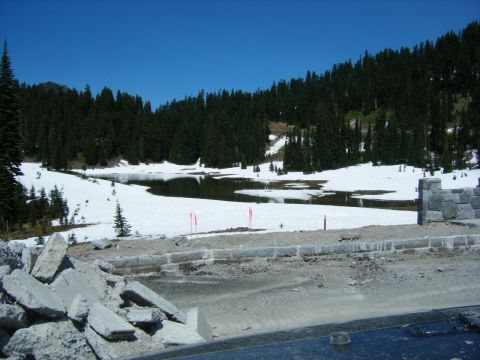 2005 Jeep Wrangler - A scenic view of a partially snow-covered lake surrounded by evergreen trees under a clear blue sky. In the foreground, there are piles of…