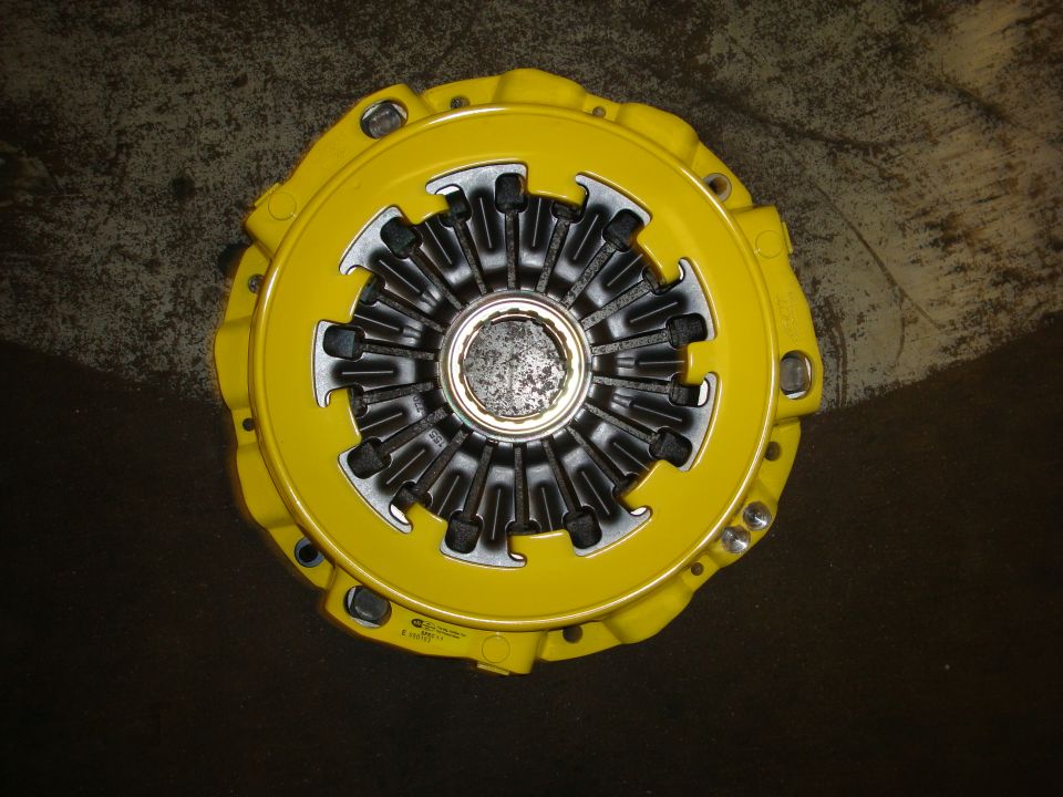 Yellow clutch pressure plate with metallic center and black fingers.