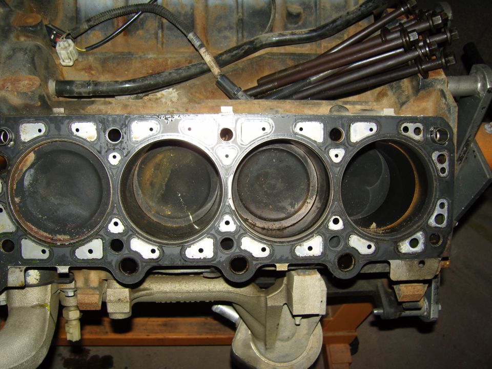 Disassembled engine block deck with head gasket and cylinder bores