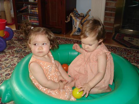 2000 Ford Crown Victoria - Two young girls are sitting inside a green inflatable pool. One girl on the left has curly brown hair and is wearing an orange dress with w…