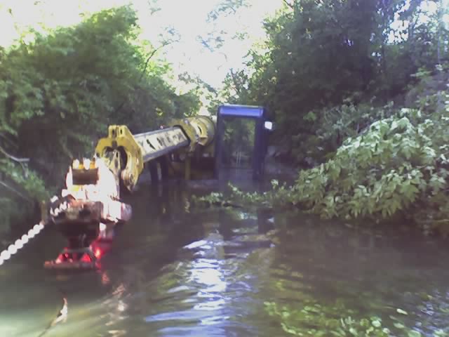 Photo of an excavator and equipment in flooded brush during recovery