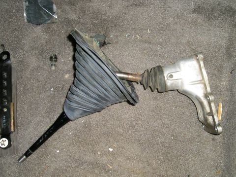 1986 Toyota Hilux - A disassembled Toyota Hilux shifter assembly with a black rubber boot and a silver metal bracket is laid out on a gray carpeted surface. A…