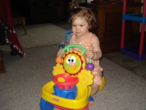 2000 Ford Crown Victoria - A young child is playing with a colorful Fisher-Price toy that resembles a sun and has wheels. The child is sitting on the floor, holding o…