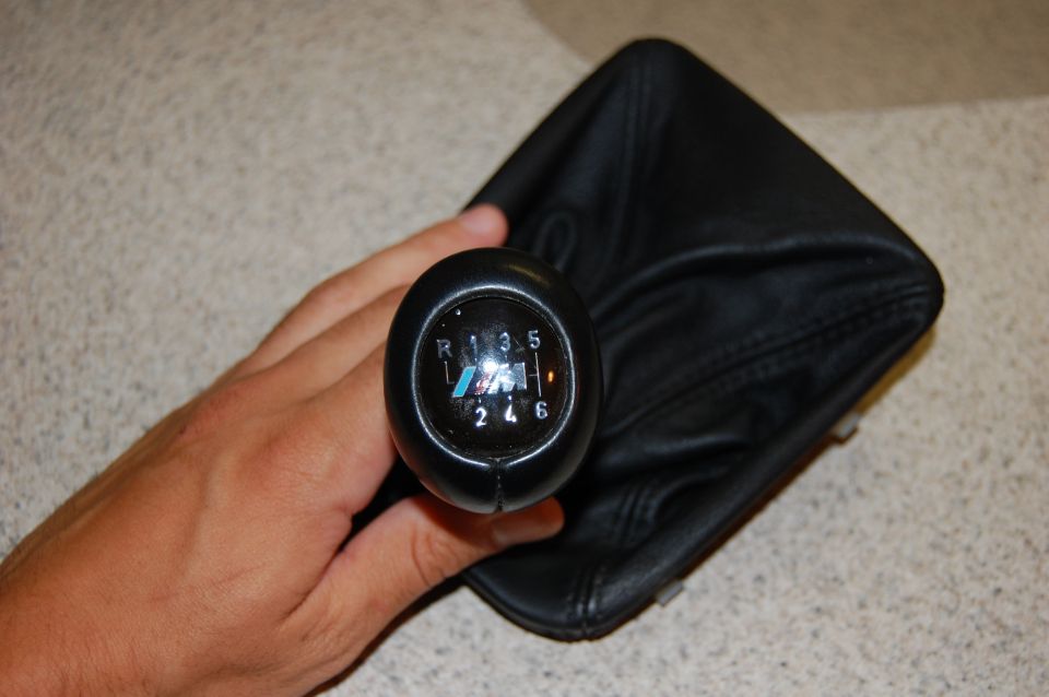 BMW M 6-speed shift knob and black leather shift boot held by a hand