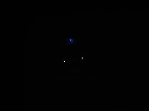 1996 Ford Bronco - A dark image with a small, blurry blue light at the top and two small white lights below it. The context suggests this may be a vehicle, bu…