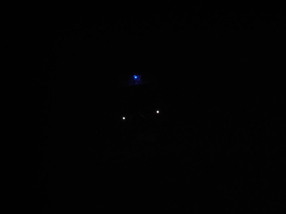 Dark image with faint lights, possibly a vehicle at night.