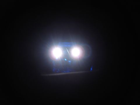 1996 Ford Bronco - The headlights of a vehicle are illuminated in the dark, with blue lights visible below them.