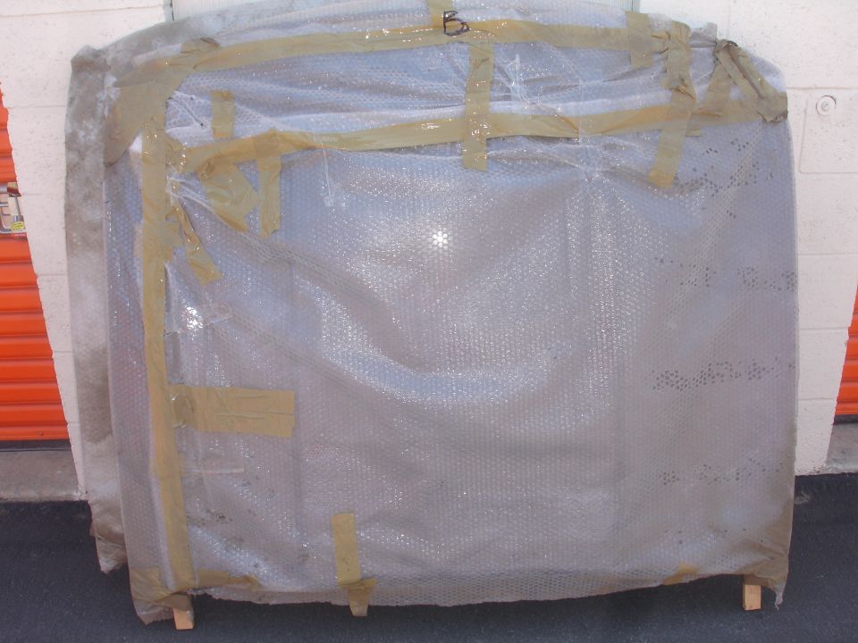Windshield wrapped in bubble wrap and tape, resting on wooden blocks.