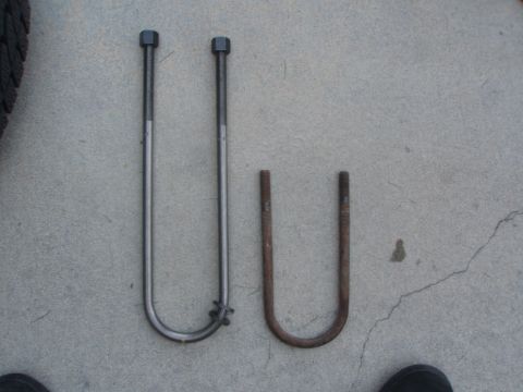 1987 Ford Bronco - Two U-bolts are shown on a concrete surface. The U-bolt on the left is longer and appears to be made of polished metal, while the U-bolt on…