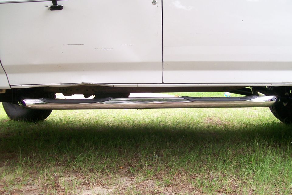 White truck side view with chrome step bar and dented lower body panel