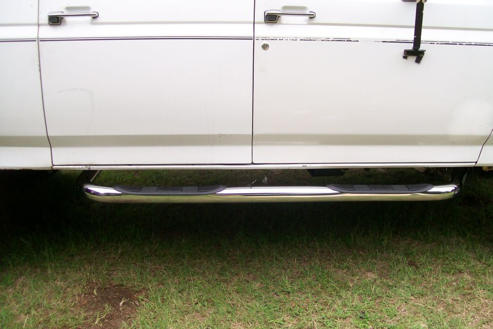 White four-door truck side view with chrome side steps.