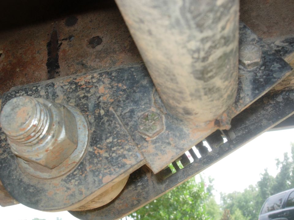 Close-up of rusty vehicle undercarriage with bolt and bracket.