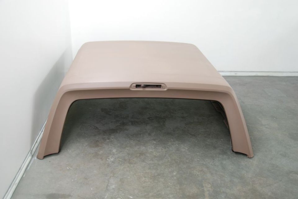 Photo of the top of a tan fiberglass truck cap on a concrete floor