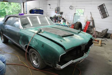 1996 Ford Bronco - Photograph of a green classic convertible undergoing restoration in a shop, not a document.