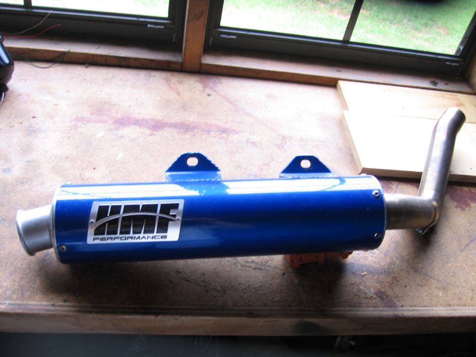 Blue HMF Performance exhaust muffler on a wooden surface.