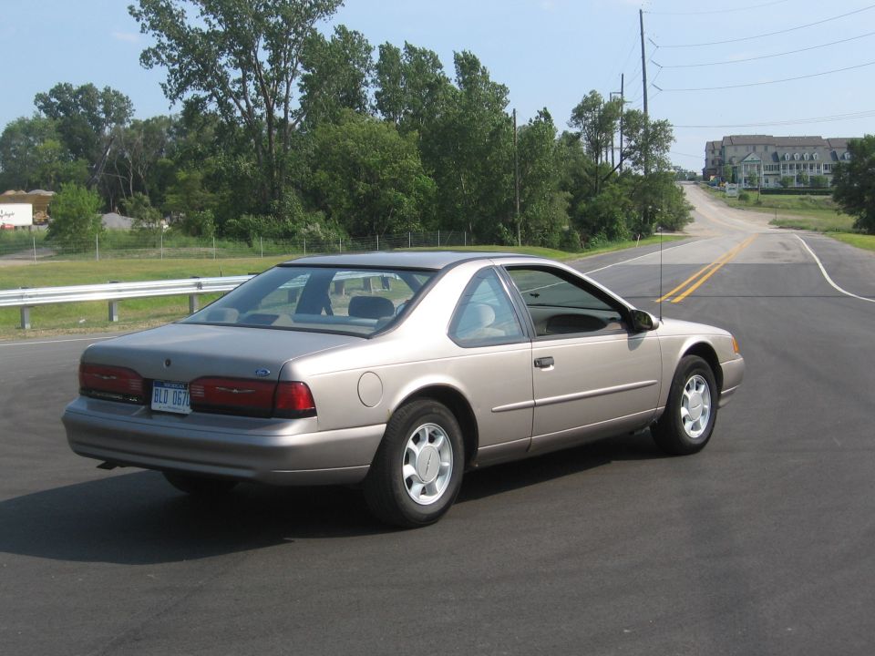 Silver 1995 Ford Thunderbird parked on a road, rear passenger side view.