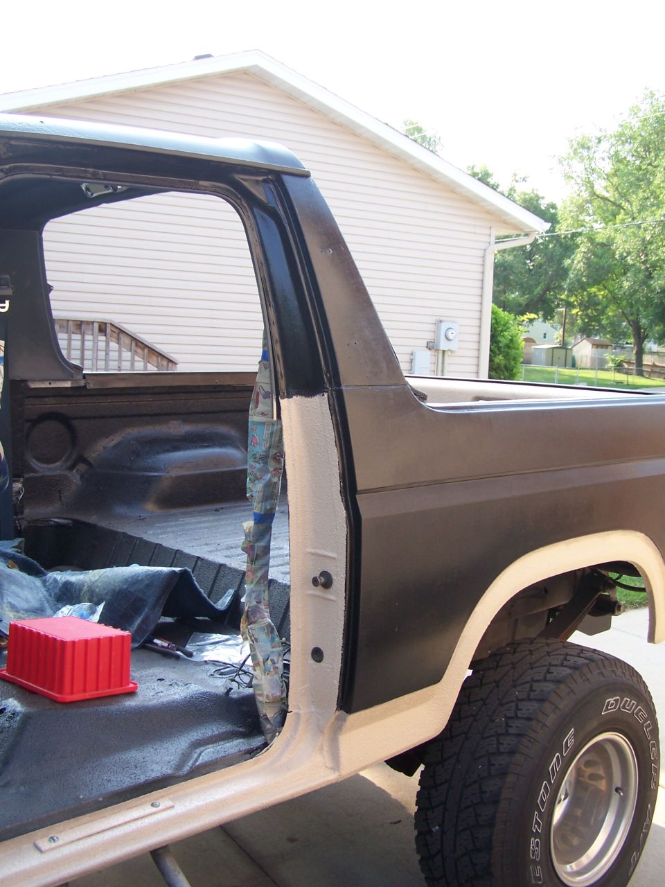 1986 Ford Bronco driver's side door open, showing interior and bed with spray liner.