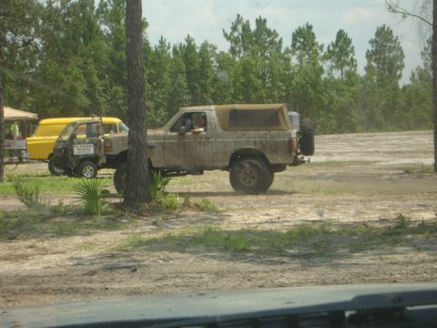1989 Ford Bronco - A mud-splattered 1989 Ford Bronco is seen parked next to a yellow vehicle in an outdoor setting.