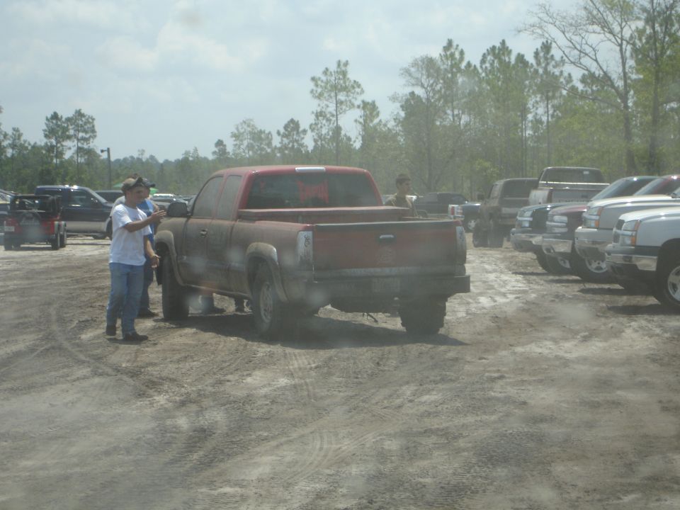 Red pickup truck parked in a dirt lot with other vehicles