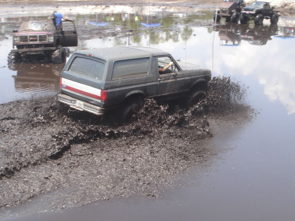 Ford Bronco driving through mud pit, another truck in background