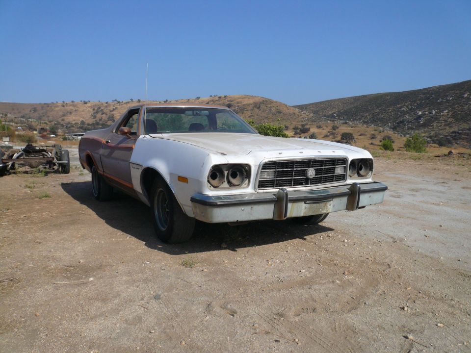 1975 Ford Ranchero with white front end and brown rear, missing headlights, parked on dirt