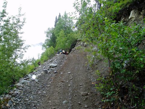 2000 Ford E350 - An ATV navigates a challenging, steep, and rocky trail through a wooded mountainside.