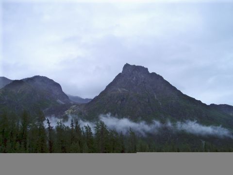 2000 Ford E350 - A dramatic mountain landscape under a cloudy sky, with a dense forest in the foreground.